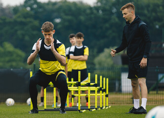 Group of Football Players on Agility Training. Young Coach Giving Advices to Player on Training. Coaching Soccer in Teenage Football Team