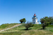 view of the Hundested lighthouse on ist grassy hill under a blue sky