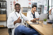 © sofiko14 - Group of competent doctors with laptops and tablets having meeting at medical office. International specialists sharing with knowledge. African male doctor shows thumb up