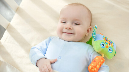 Wall Mural - Portrait of happy smiling baby boy lying in crib at morning