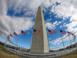 © Evgenia Parajanian - Wide angle perspective of Washington, DC National monument and flags of USA on blue sky background.