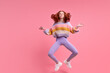 © alfa27 - pretty redhead lady jumping high sitting air in lotus pose practicing morning yoga wearing casual outfit isolated pastel pink color background, portrait. Calm caucasian female meditating