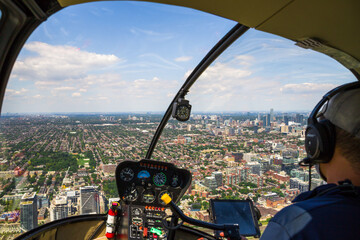 Helicopter cockpit flies in Toronto city downtown, with pilot arm and control board inside the cabin. Ontario, Canada