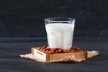 Almond milk with almond kernels. Alternative milk for vegetarians. Milk in a glass on a gray background.