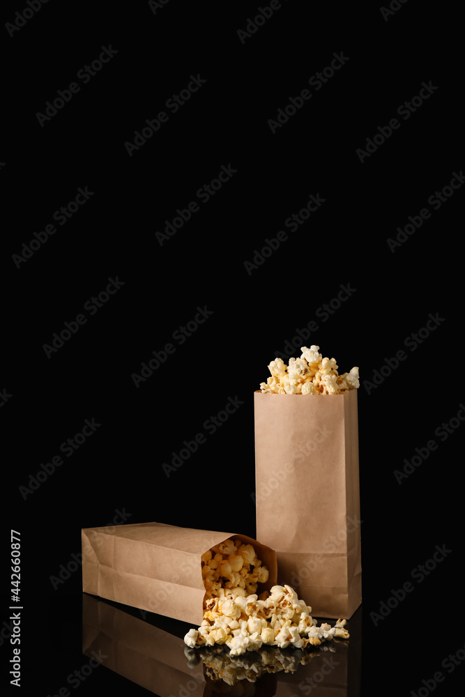 Paper bags with tasty popcorn on dark background