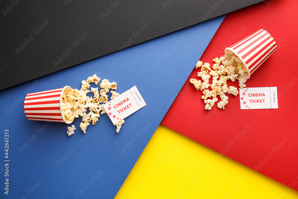 Buckets with tasty popcorn and cinema tickets on color background