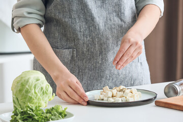 Wall Mural - Woman adding spices onto feta cheese on plate, closeup