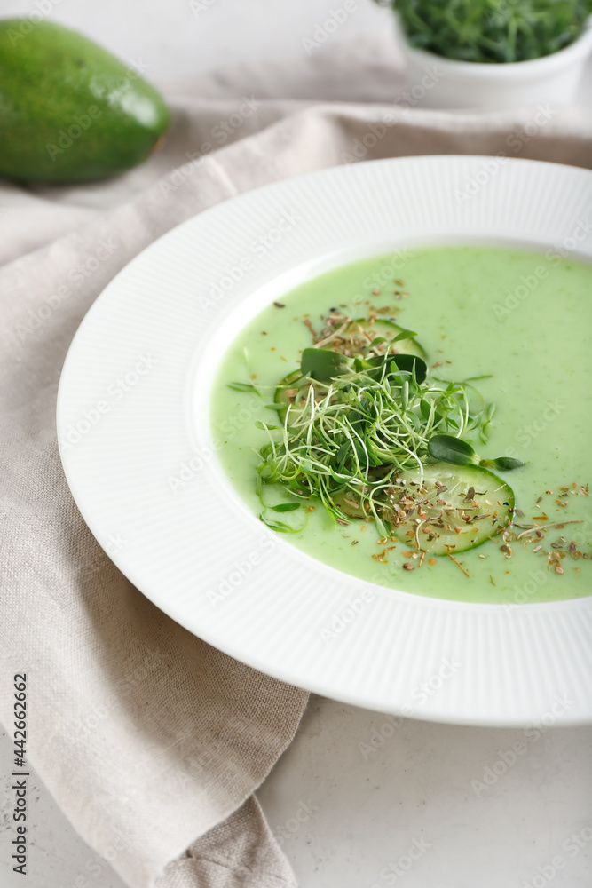 Plate with green gazpacho on light background, closeup