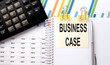 © Iryna - BUSINESS CASE text, written on a sticker with calculator,pen on the chart background.