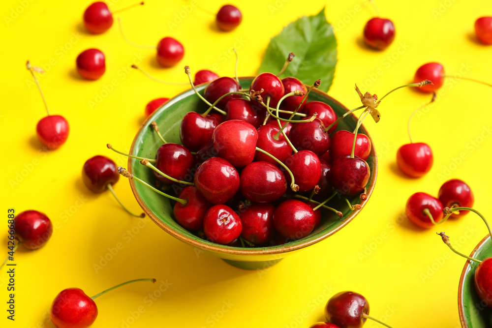 Bowl with tasty ripe cherry on color background