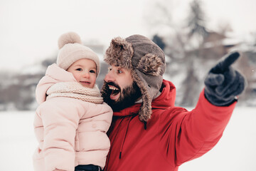 Canvas Print - Handsome bearded young dad and his little cute daughter are having fun outdoor in winter. Enjoying spending time together. Family concept