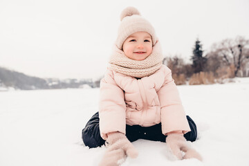 Canvas Print - Happy laughing girl wearing a pink jacket, scarf and hat, playing in a beautiful snowy winter walk. Girl enjoys winter, frosty day. Playing with snow on winter holidays. Winter holidays concept.