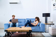 © ADDICTIVE STOCK - Young couple spending free time with gadgets in modern living room