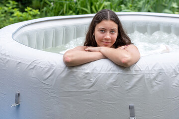 Wall Mural - gorgeous teenage girl with long, dark hair relaxes in the garden inflatable pool with jacuzzi