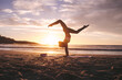 Woman doing yoga pose handstand on beach