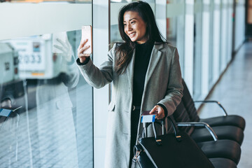 Wall Mural - Female traveler taking selfie at airport terminal