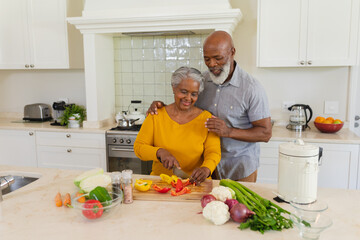 Senior african american couple cooking together in kitchen smiling