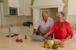 © wavebreak3 - Senior caucasian couple cooking together and using laptop in kitchen