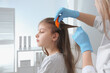 © New Africa - Doctor using nit comb on girl's hair in clinic. Anti lice treatment