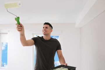 Poster - Man painting ceiling with roller in room. Space for text