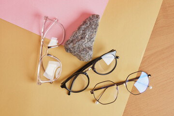 Wall Mural - eye glasses on a concrete podium on a pink and beige background, trend composition, black stylish eye glasses,