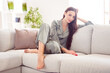 © deagreez - Full length photo of young attractive girl happy positive smile sitting couch living-room wear nightwear home
