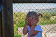 Play hide-and-seek. The little girl jokes and hides her face with her hands. Children's game for toddlers to hide from mom. Have fun in a happy childhood.