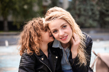 Wall Mural - Mom and daughter are whispering while walking around the city