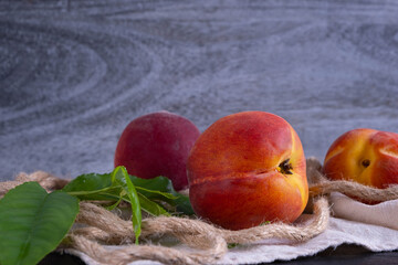 Wall Mural - juicy and ripe peaches and green foliage lie on a napkin