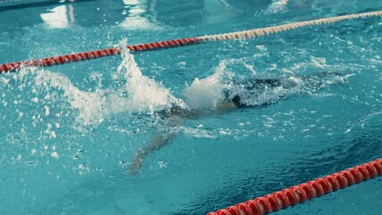 Canvas Print - Successful Male Swimmer Racing, Swimming in Olympic Swimming Pool. Professional Athlete Determined to Win Championship using Butterfly Style. Colorful Cinematic Shot. Side View Tracking Slow Motion