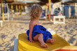 A small child is looking for parents on the beach. Leave one girl on a lounger in a towel after bathing. Sunbathe and dry in the sun.