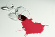Overturned glass and spilled wine on white background