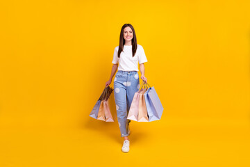 Poster - Full size photo of happy smiling beautiful cheerful girl go shopping shopaholic isolated on yellow color background