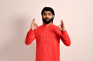 Wall Mural - young Indian Guy feeling shocked, amazed and surprised, showing okay sign with both hands