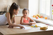 © Olena Shvets - Older sister helping younger sister to do her homework for school