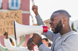 © ADDICTIVE STOCK - Black man protesting with megaphone in street