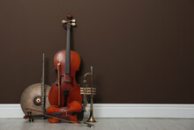 Set Of Different Musical Instruments Near Brown Wall Indoors, Space For Text