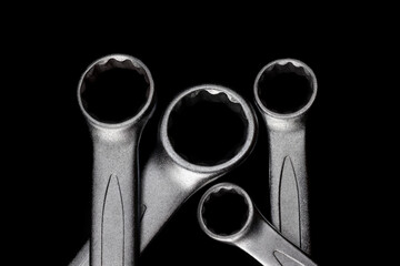 Wall Mural - Four steel closed end ring wrenches isolated on black background closeup