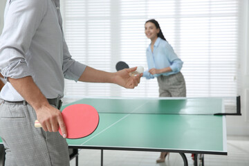 Wall Mural - Business people playing ping pong in office, focus on tennis racket