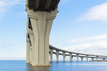 View of the big rounded motorway, Controlled-access highway bridge against a background of blue sky with clouds. The road passing over the sea bay near the coast of the city. Saint Petersburg, Europe