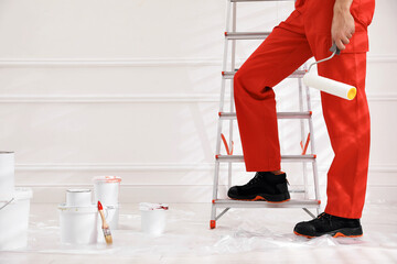 Wall Mural - Worker with roller near ladder indoors, closeup. Space for text