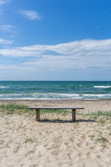 Poster - vertical view of a wooden bench on an idyllic secluded empty beach