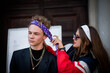 Cute fun curly teenage boy and girl wearing stylish 90s fashion clothes with chains around neck. Youth subculture. The girl puts a bandana on the guy. ap artist from new school.