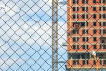 Metal Mesh Fence On The Background Of A Residential Building Under Construction