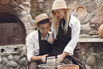 People making a vaze from a clay on a pottery's machine