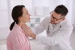 © New Africa - Doctor examining thyroid gland of patient in hospital