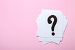 Paper cards with question marks on pink background. Pile of question marks, top view with place for text