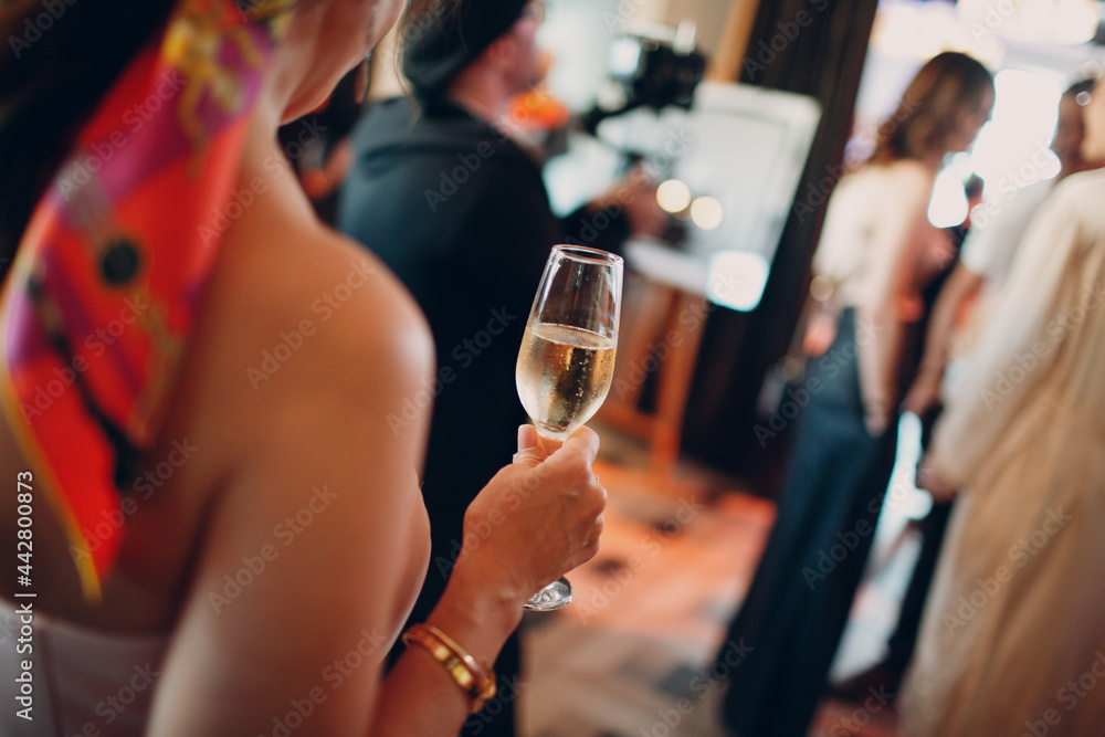 rear view woman holding misted chilled glass of champagne in hand at party. - obrazy, fototapety, plakaty 