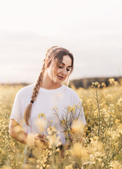 Happy young woman walking in yellow field on summer day