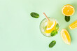 Ice lemon water or lemonade with mint on a green background. A glass of fresh fruit drink for summer heat.